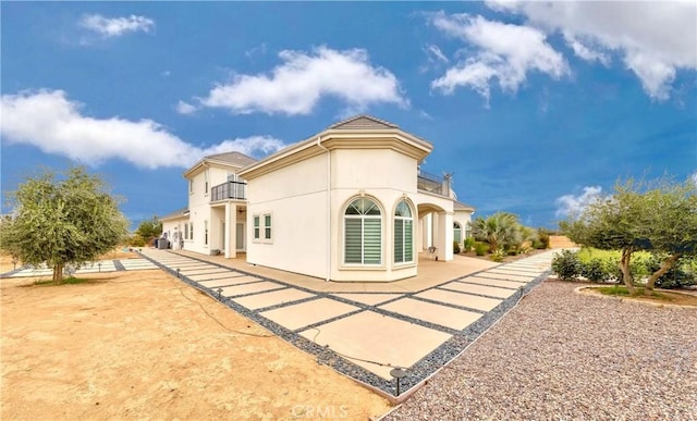 back of property with a balcony and a patio