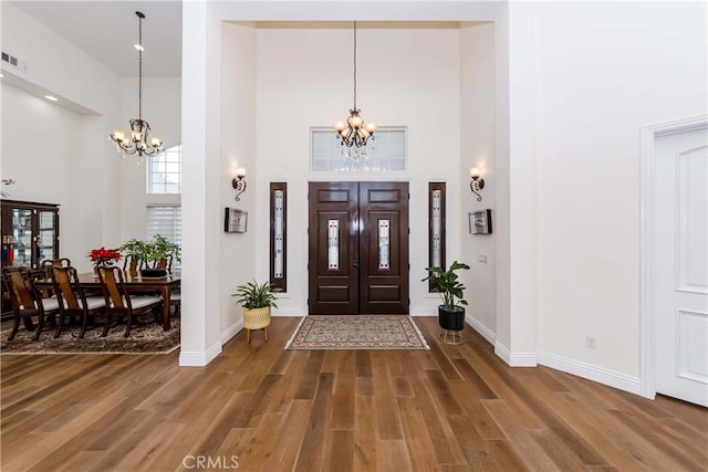 foyer featuring a chandelier, wood-type flooring, and a towering ceiling