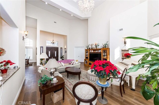 living room with a towering ceiling, a chandelier, and hardwood / wood-style floors