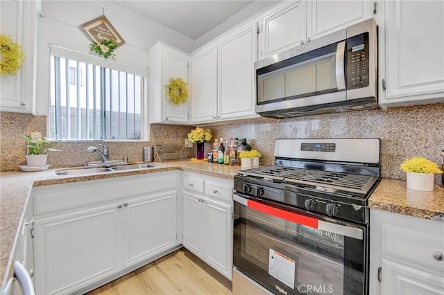 kitchen featuring tasteful backsplash, white cabinetry, appliances with stainless steel finishes, and sink