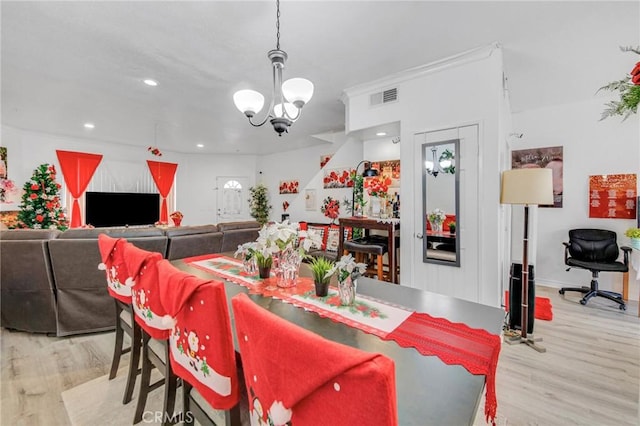 dining area featuring a notable chandelier, crown molding, and light wood-type flooring