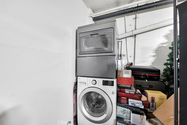 clothes washing area with stacked washing maching and dryer and laundry area