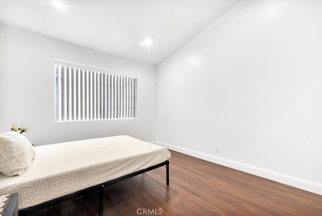 bedroom with baseboards, vaulted ceiling, and dark wood-style flooring