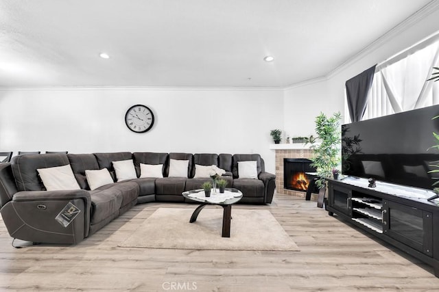 living room with recessed lighting, crown molding, wood finished floors, and a lit fireplace