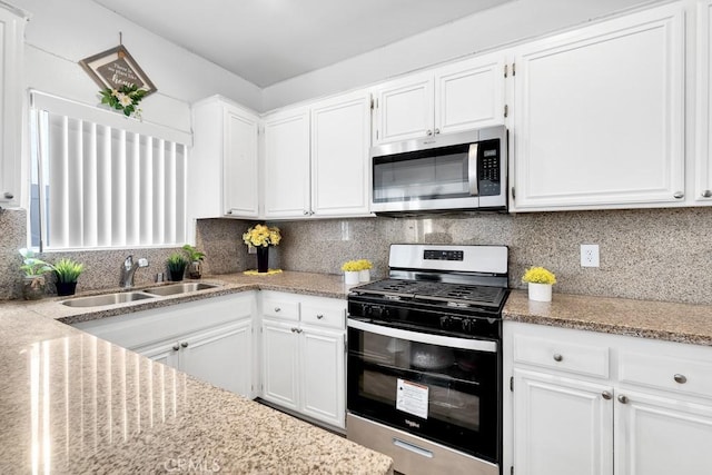 kitchen with backsplash, white cabinetry, stainless steel appliances, and a sink