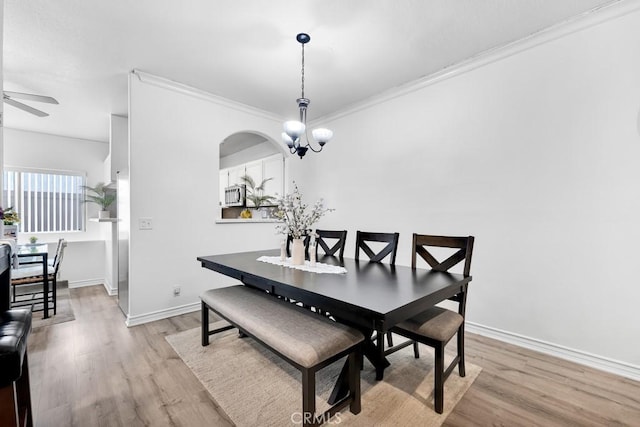 dining room with ornamental molding, baseboards, light wood finished floors, and ceiling fan with notable chandelier