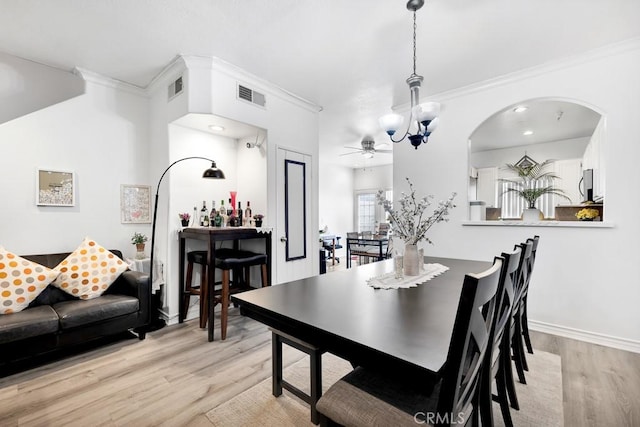 dining space featuring light wood-style floors, visible vents, ornamental molding, and an inviting chandelier