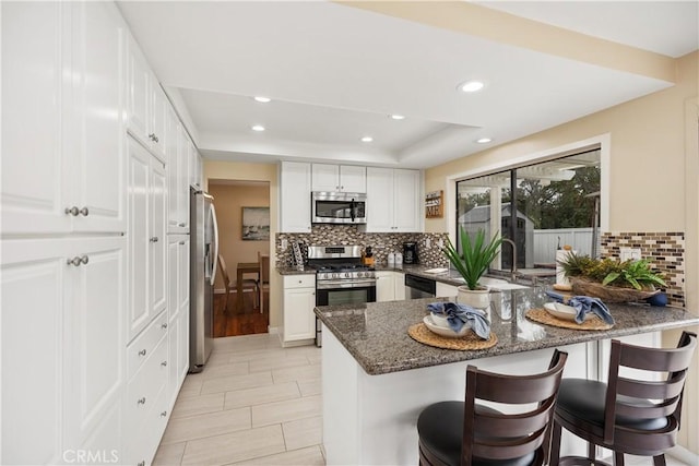 kitchen with white cabinetry, stainless steel appliances, kitchen peninsula, and a breakfast bar