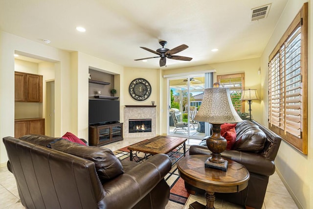 tiled living room with ceiling fan and a tiled fireplace