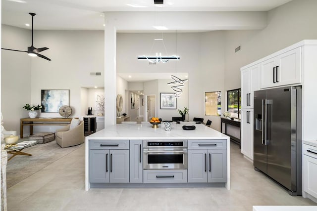 kitchen with appliances with stainless steel finishes, ceiling fan with notable chandelier, white cabinetry, gray cabinetry, and light stone countertops