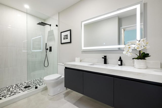 bathroom with vanity, tile patterned floors, toilet, and tiled shower