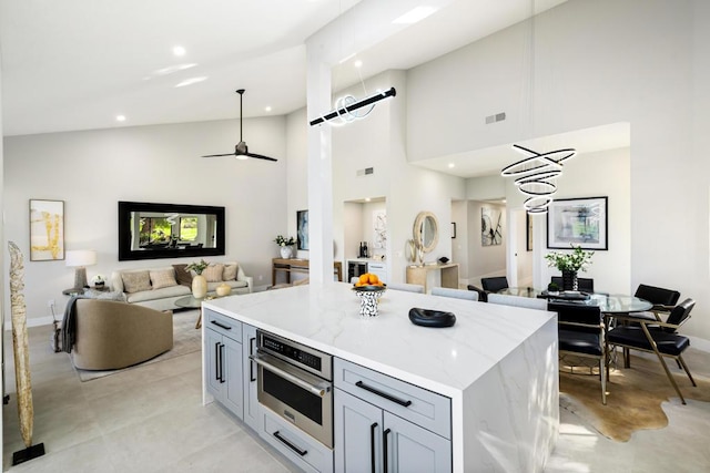 kitchen with gray cabinets, a kitchen island, light stone countertops, and oven