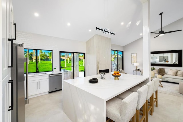 kitchen featuring a kitchen bar, white cabinetry, appliances with stainless steel finishes, a wealth of natural light, and ceiling fan