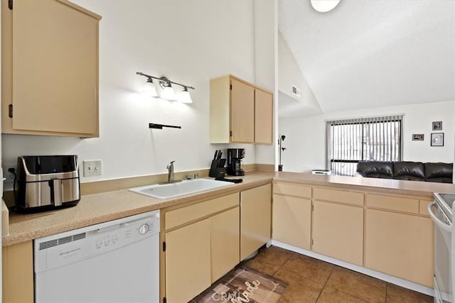 kitchen with kitchen peninsula, white appliances, dark tile patterned flooring, vaulted ceiling, and sink