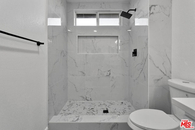 bathroom featuring tiled shower and toilet