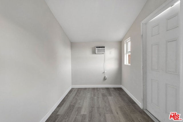 unfurnished room with lofted ceiling, wood-type flooring, and a wall mounted air conditioner