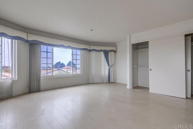 unfurnished bedroom featuring a closet, hardwood / wood-style flooring, and multiple windows