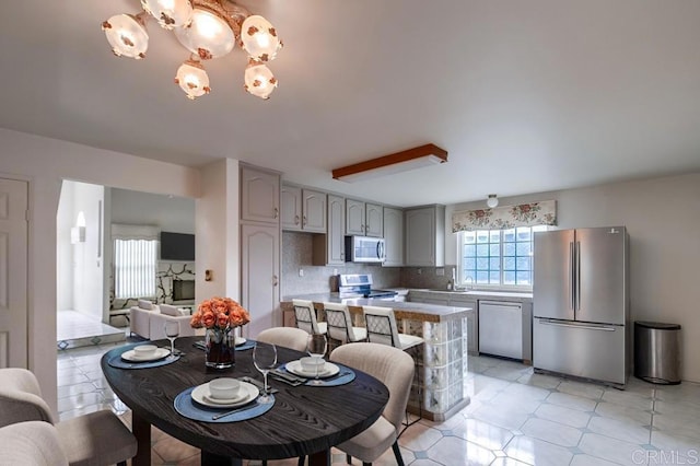 kitchen with tasteful backsplash, a notable chandelier, gray cabinetry, and stainless steel appliances