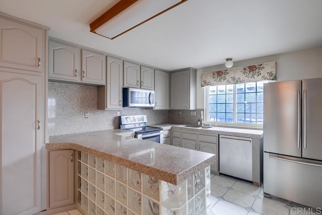 kitchen with backsplash, kitchen peninsula, sink, appliances with stainless steel finishes, and gray cabinetry