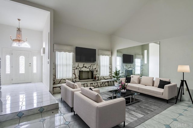 living room with a wealth of natural light, a notable chandelier, tile patterned floors, and a stone fireplace