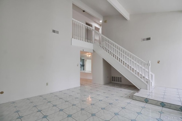 stairs with tile patterned floors, beamed ceiling, and a high ceiling