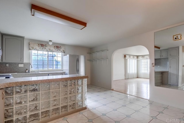 kitchen with gray cabinetry, sink, tasteful backsplash, and stainless steel refrigerator