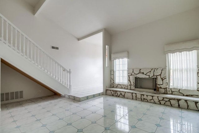 interior space featuring light tile patterned floors, a high ceiling, and a stone fireplace