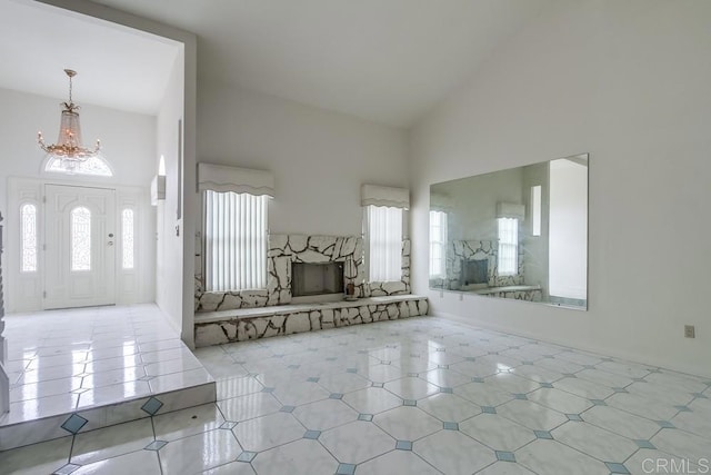 tiled entrance foyer with an inviting chandelier, a stone fireplace, and high vaulted ceiling