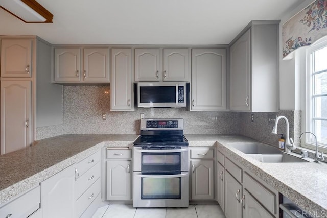 kitchen with light tile patterned floors, sink, appliances with stainless steel finishes, and tasteful backsplash