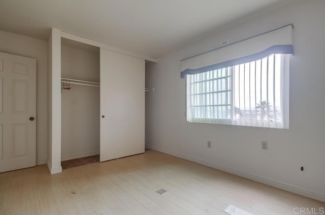 unfurnished bedroom featuring a closet and light wood-type flooring