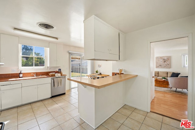 kitchen with white dishwasher, white cabinets, stainless steel dishwasher, and light tile patterned flooring