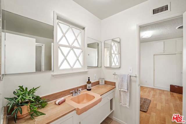 bathroom with a textured ceiling, hardwood / wood-style flooring, and vanity