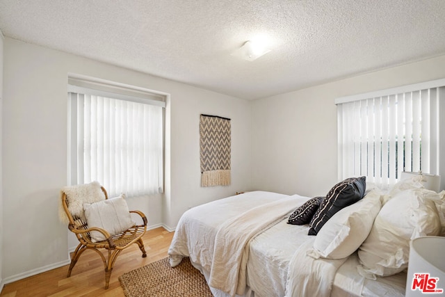 bedroom with hardwood / wood-style flooring and a textured ceiling