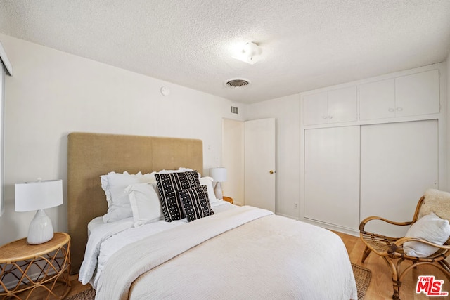 bedroom featuring a closet, a textured ceiling, and hardwood / wood-style flooring