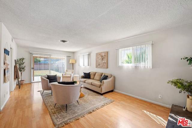 living room featuring light wood-type flooring and a textured ceiling