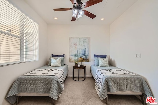 bedroom featuring ceiling fan, light colored carpet, and multiple windows