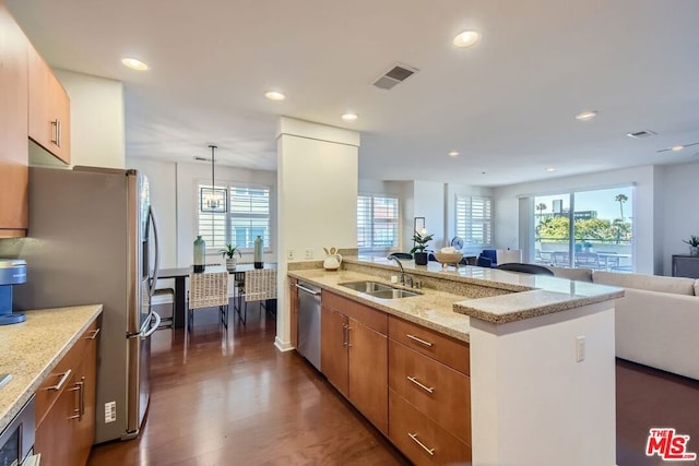 kitchen with decorative light fixtures, sink, light stone countertops, appliances with stainless steel finishes, and dark wood-type flooring