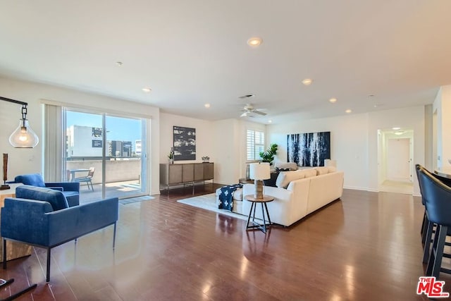 living room featuring ceiling fan, dark wood-type flooring, and a healthy amount of sunlight