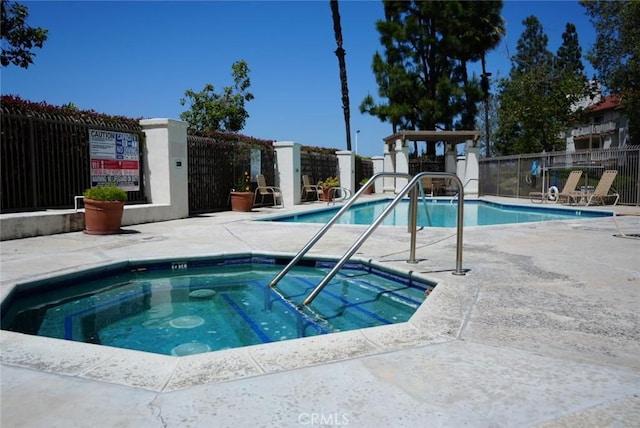 view of swimming pool featuring a hot tub and a patio area