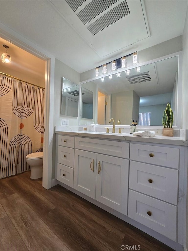 bathroom with toilet, vanity, and hardwood / wood-style flooring