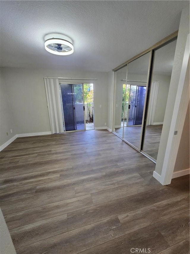 empty room with a textured ceiling and dark hardwood / wood-style floors