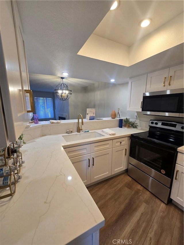 kitchen featuring white cabinets, kitchen peninsula, appliances with stainless steel finishes, and sink