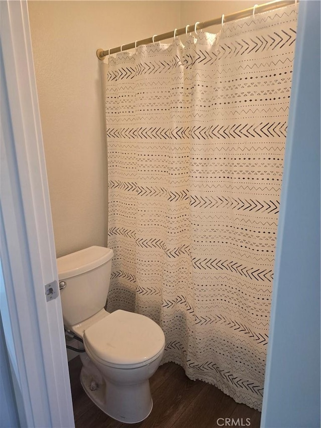 bathroom with toilet, wood-type flooring, and a shower with shower curtain