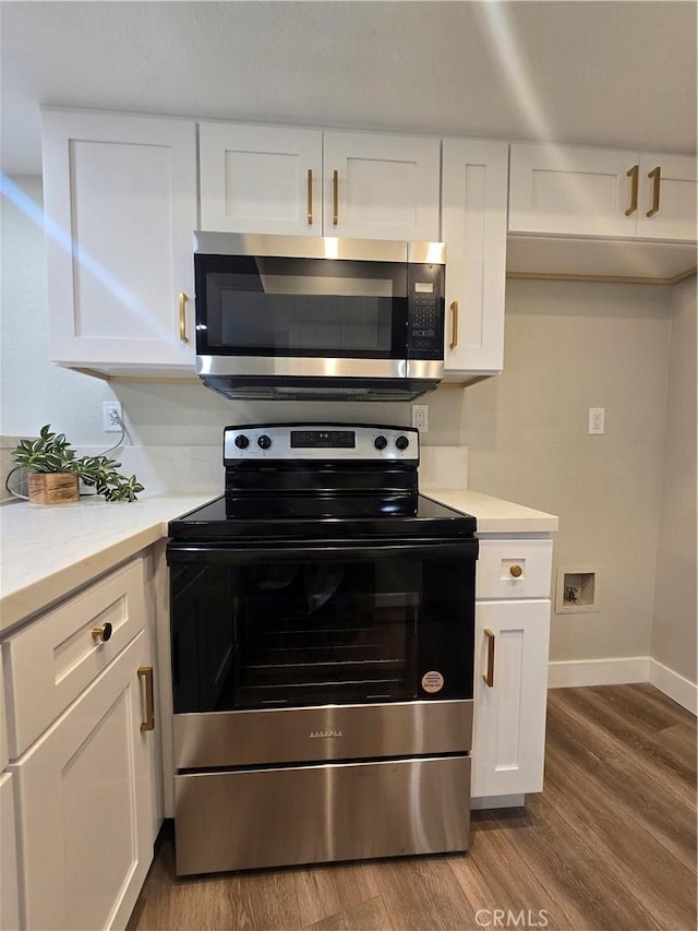 kitchen featuring white cabinets, appliances with stainless steel finishes, and hardwood / wood-style flooring