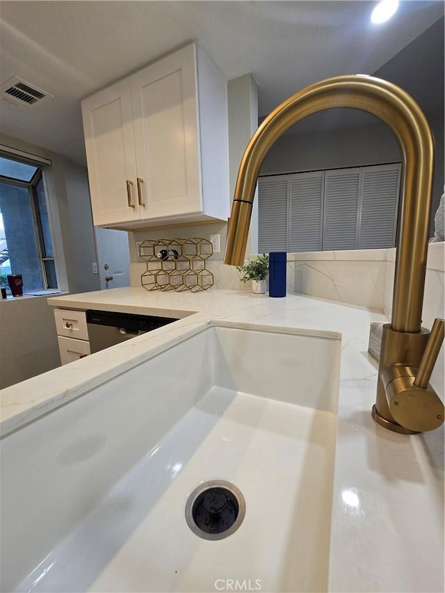 details featuring light stone counters, sink, white cabinets, and stainless steel dishwasher