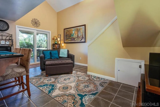 sitting room featuring high vaulted ceiling and dark tile patterned flooring