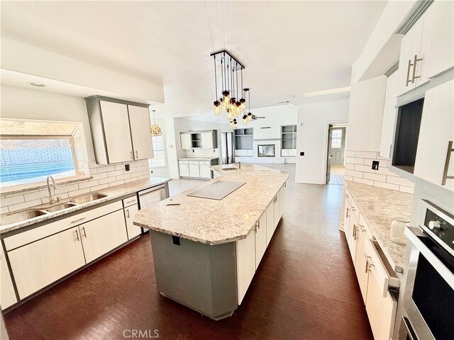 kitchen with oven, a kitchen island, pendant lighting, sink, and a healthy amount of sunlight