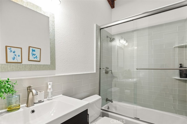 full bathroom featuring toilet, vanity, tile walls, and bath / shower combo with glass door