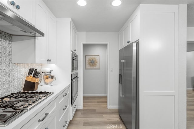 kitchen with extractor fan, decorative backsplash, white cabinetry, light wood-type flooring, and stainless steel appliances