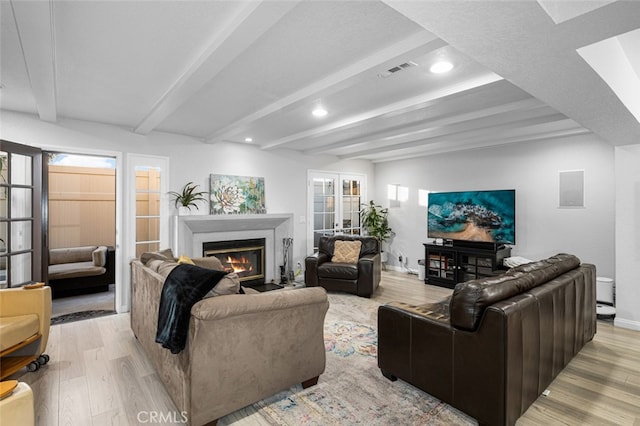 living room with light hardwood / wood-style flooring, beam ceiling, and french doors